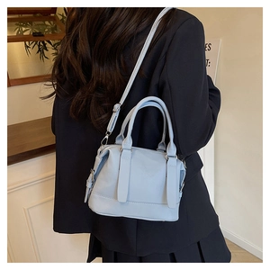 Dettaglio borsa azzurra in ecopelle indossata con un blazer blu scuro elegante