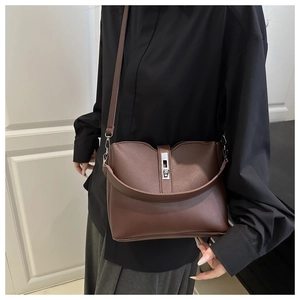Detail of dark brown bucket bag with silver metal bar clasp and slim leather handle