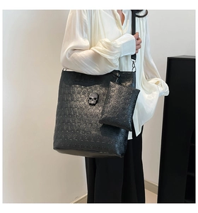 Close-up of black tote bag featuring embossed skull texture and silver skull ornament