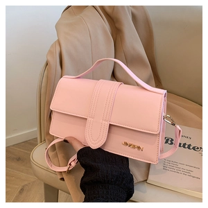 Détail du sac à rabat vintage rose avec boucles dorées sur une chaise et une veste