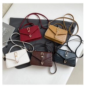 Flat lay of five faux crocodile texture handbags in red, brown, white, and black colors
