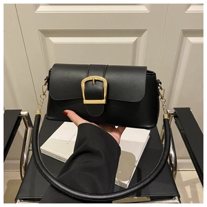 Detail view of a black leather handbag featuring a large gold U-shaped metal buckle