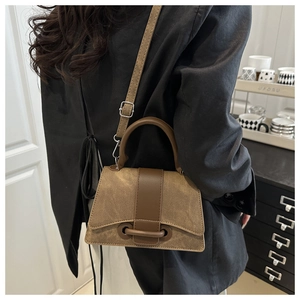 Detail of a brown patchwork canvas and leather handbag worn as a stylish crossbody bag