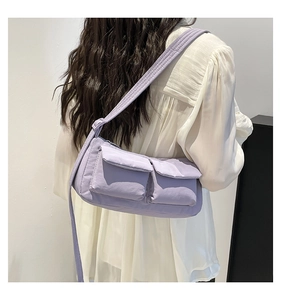 Detail view of a lavender nylon messenger bag with double front utility pockets on a model