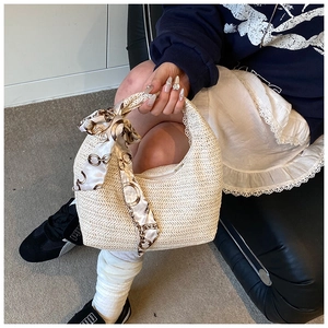 Détail d'un sac à main en paille en demi-lune avec poignée décorative en foulard de soie