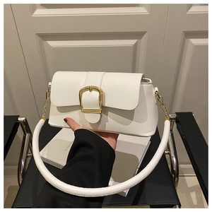 Detail of the white crossbody bag featuring a large golden horseshoe buckle and strap