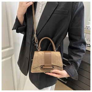 Detail view of the vintage brown trapezoid bag with structured handle and matte leather finish