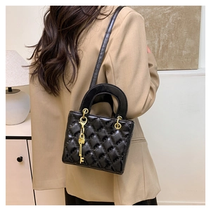 Detail of black quilted leather handbag with gold key charm and circular handle decoration