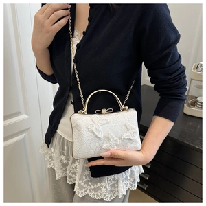 Close-up of white lace embroidery evening bag with 3D butterfly appliques and gold handle