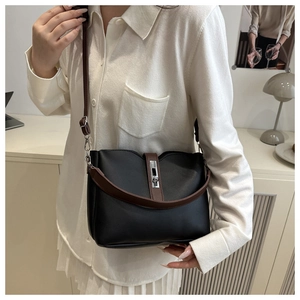 Detail view of black vintage bucket bag with brown strap on model for size reference