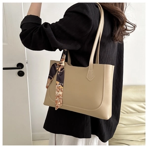 Détail du sac cabas beige avec un foulard en soie violet sur la poignée en cuir