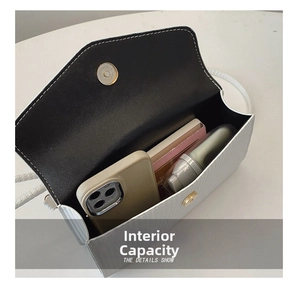 Détail de la capacité interne du sac blanc montrant un téléphone et du maquillage