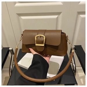 Detail of vintage brown leather handbag featuring a large golden horseshoe buckle and strap