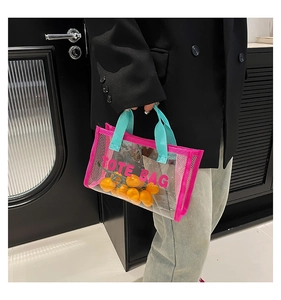 Detail of transparent PVC tote bag with pink mesh trim and blue handles held by a person