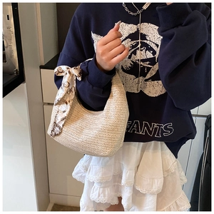 Détail du sac en paille en demi-lune avec foulard en soie et sweat à fleurs