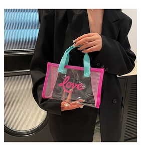 Close-up of clear PVC handbag with pink Love print and contrasting mint green handles