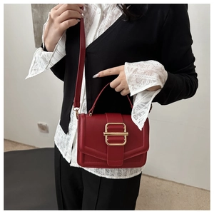 Detail of red square handbag featuring golden double-square buckle and crossbody strap