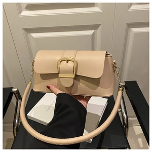 Detail of beige faux leather crossbody bag with a large golden buckle and retro chain
