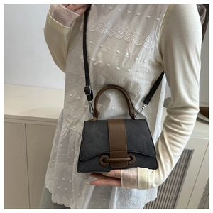 Detail of vintage mini crossbody bag with dark grey suede finish and brown leather handle