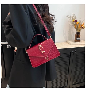 Macro detail of dark red crocodile pattern leather bag with U-shaped metal buckle