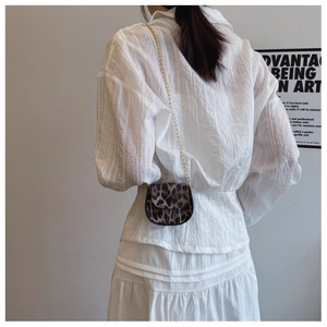 Mini-Satteltasche mit Leopardenmuster und Goldkette an der Schulter des Models