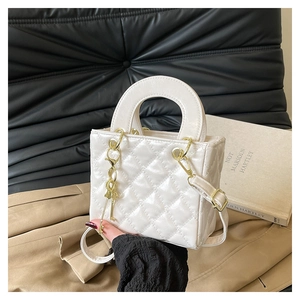 Détail du mini sac en cuir verni blanc avec motif matelassé et détails dorés brillants