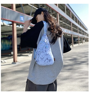 Detail of light blue marble pattern nylon chest bag with adjustable strap and orange label