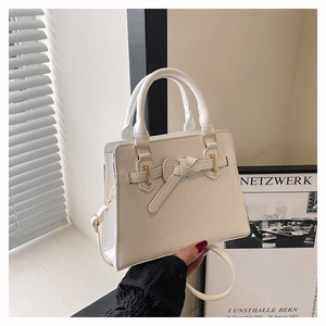 Detail of white structured handbag featuring a leather bow and gold metal buckle design