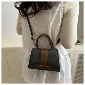 Detail of retro crossbody bag with dark grey texture and brown leather straps
