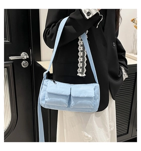 Detail of light blue nylon crossbody bag with dual utility pockets and wide strap