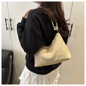 Detail of creamy pleated fabric texture and leather logo tag on a striped tote bag