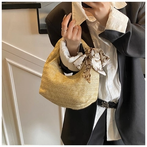 Detailed view of beige straw hobo bag with herringbone weave and patterned silk scarf