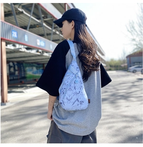 Outdoor shot showing detail of light blue marble print nylon crossbody bag on model