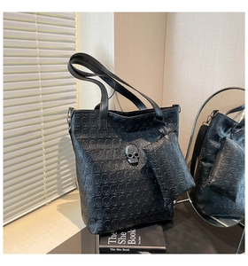 Detail of black embossed leather tote set with skull relief and metal skull stud decor