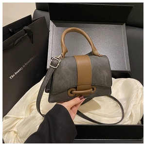 Detail of taupe crossbody bag with contrast handles and elegant gift box packaging