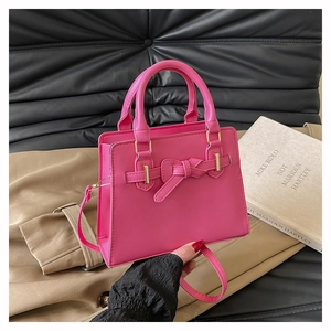 Detail of rose red leather handbag with bow buckle and versatile shoulder strap