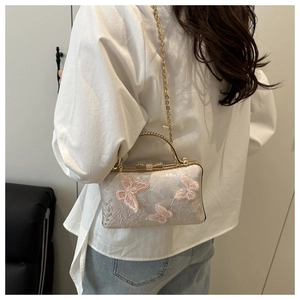 Close-up of elegant lace handbag featuring 3D pink butterfly embroidery and gold metal handle