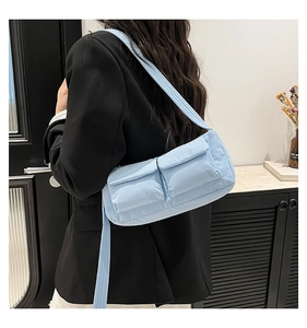 Dettaglio della borsa a tracolla trapuntata azzurra con due tasche frontali su modella