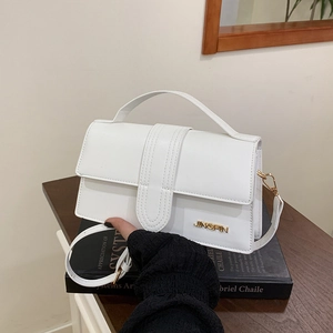 Sac à bandoulière blanc chic avec logo JINGPIN doré et poignée sur un livre noir