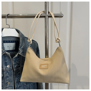 Close-up of beige pleated shoulder bag featuring striped texture and leather logo patch