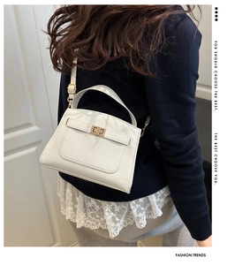 Detail of white lychee grain leather crossbody bag with golden twist lock and shoulder strap