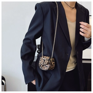 Close-up of leopard print mini saddle bag with golden chain strap on model