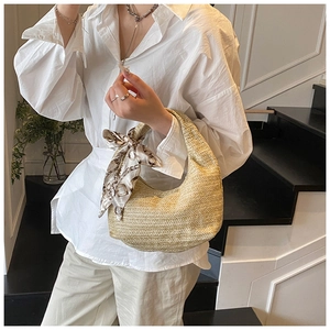 Gros plan du sac en paille demi-lune avec foulard en soie sur la poignée
