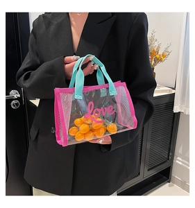 Close-up of clear PVC tote bag with pink trim, blue handle, and love lettering text