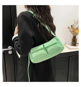 Detail view of light green quilted crossbody bag with dual front pockets and thin strap