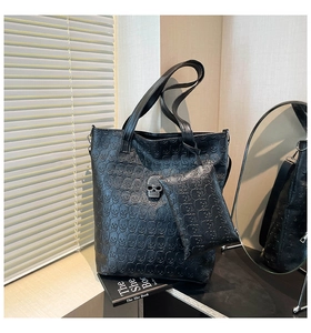 Detail of gothic black leather tote featuring skull embossing and silver rhinestone hardware