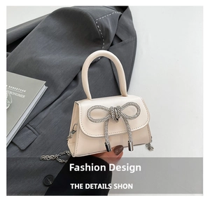Détail d'un sac à main beige élégant avec un grand nœud en strass et chaîne argentée