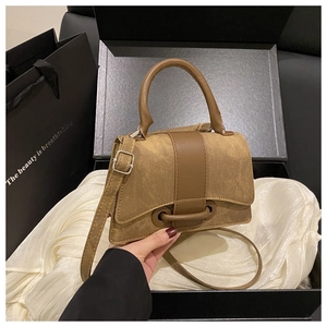 Close-up of khaki canvas handbag with brown leather straps inside a luxury gift box