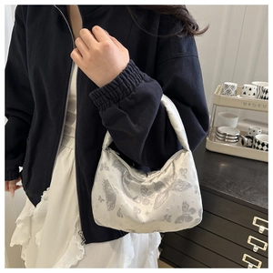 Detail of silver butterfly jacquard fabric and metal zipper on semi-moon handbag