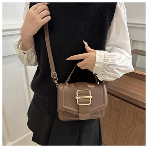 Detailed view of brown leather crossbody bag with gold metal buckle and adjustable strap